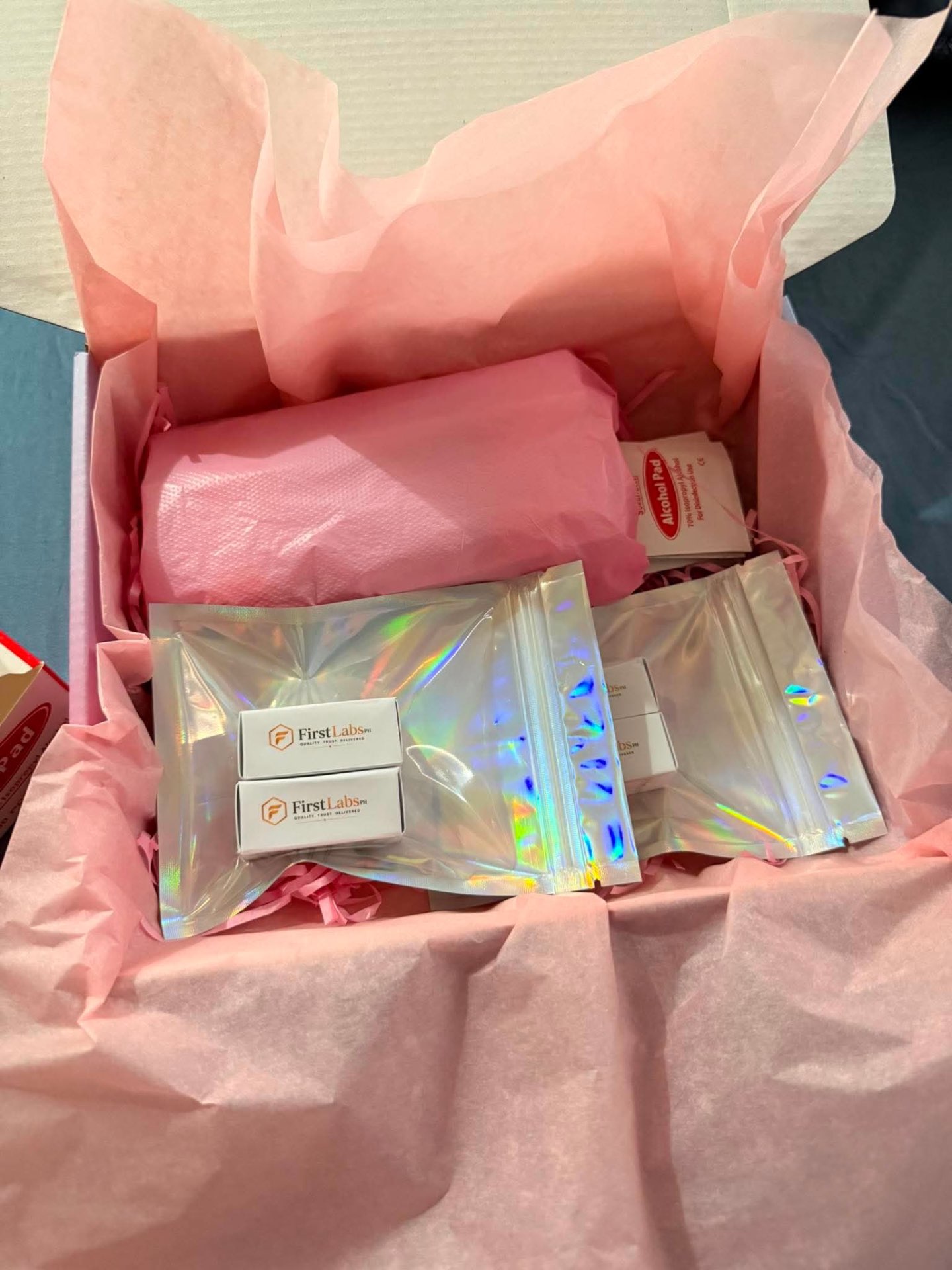 FirstLabs PH box with holographic pouches, alcohol pads, and pink tissue