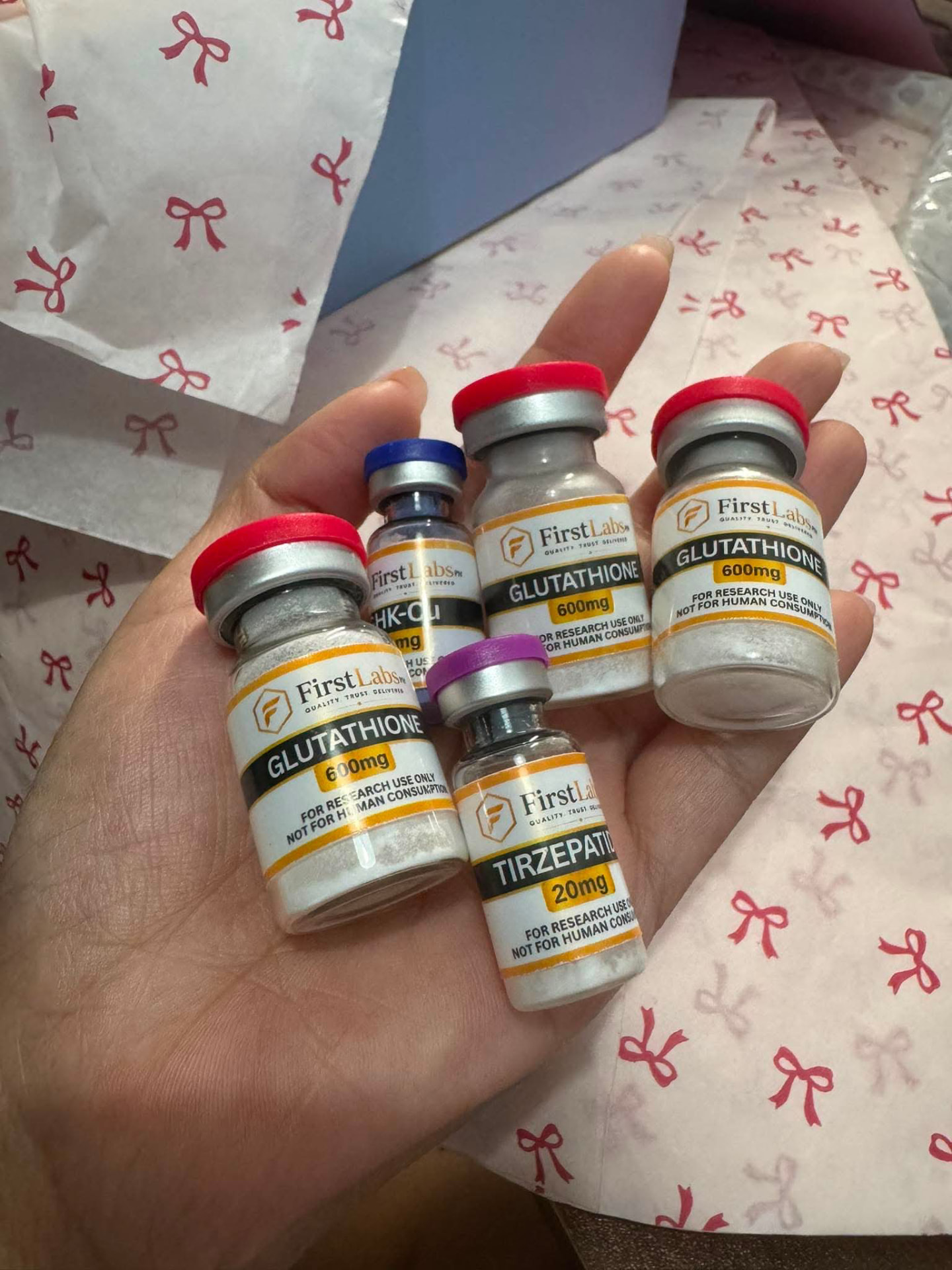 Customer holding FirstLabs PH Glutathione 600mg, GHK-Cu and Tirzepatide 20mg vials