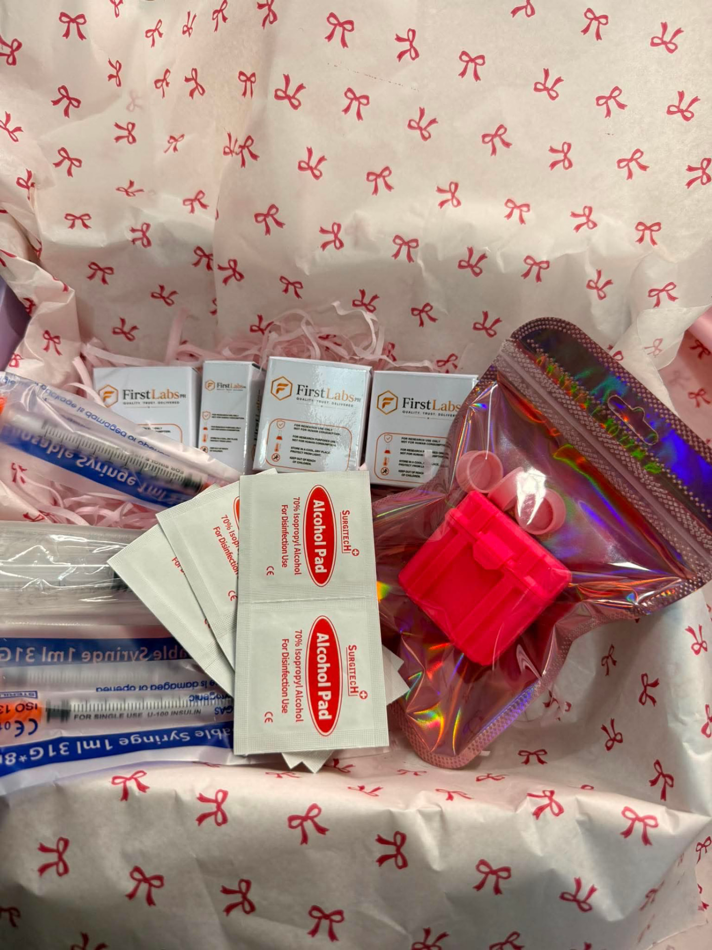 FirstLabs PH boxed vials, insulin syringes, alcohol pads and a holographic pouch with vial case on bow-print tissue
